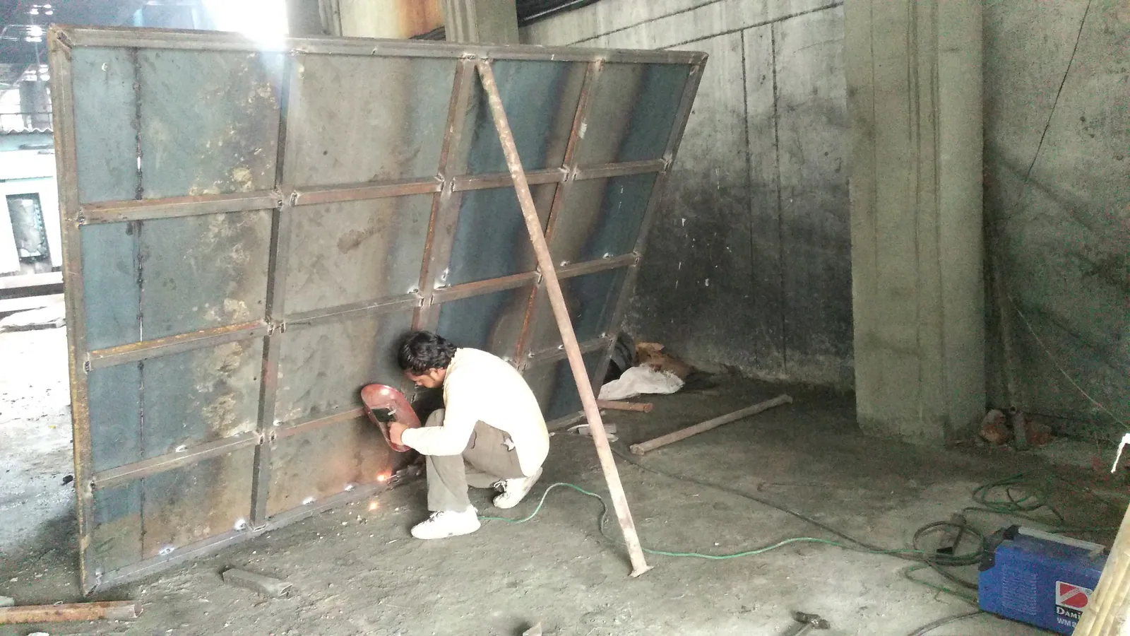 Welder fabricating a large reinforced heavy steel panel
