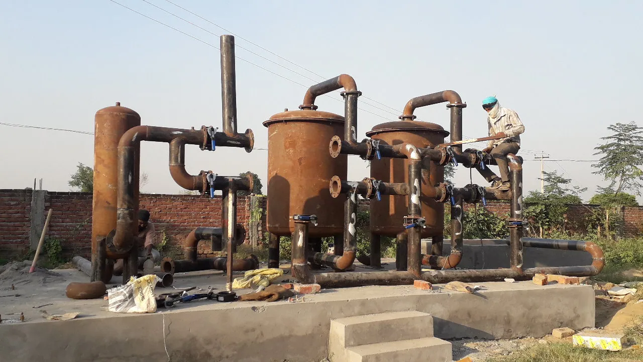 Worker installing piping on an iron removal water treatment plant
