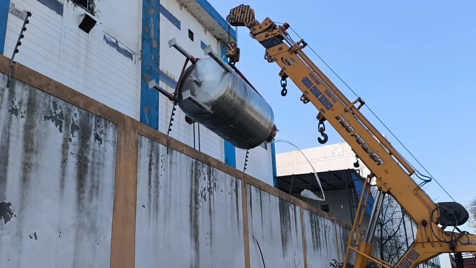 Large stainless steel tank being erected with crane support